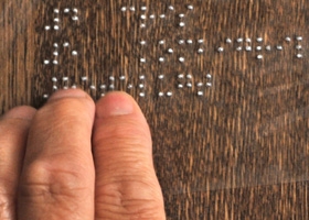 Une personne déficiente visuelle touche un marquage en braille sur une armoire.