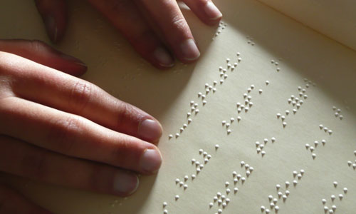 Une personne aveugle lit un livre en braille.