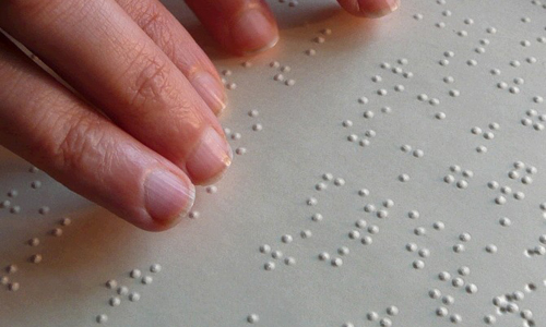 Een blind persoon leest een boek in braille.