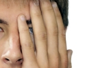Une jeune personne se cache l'oeil gauche avec sa main.