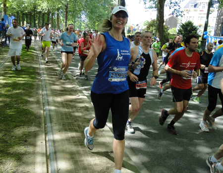 Een loopster wuift naar de supporters langsheen het parcours