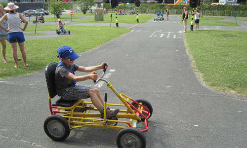 Een jongen met een visuele beperking bestuurt een gocart in het verkeerspark.