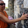 Une personne déficiente visuelle touche un mur de la cité médiévale
