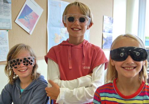 Trois enfants portent des lunettes de simulation fournies avec la BrailleBox.