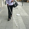 Une personne déficiente visuelle marche en rue à l'aide d'une canne blanche.