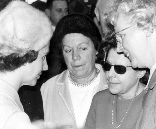 La reine Fabiola discute avec une personne déficiente visuelle lors de sa visite de la Ligue Braille le 3 mars 1970