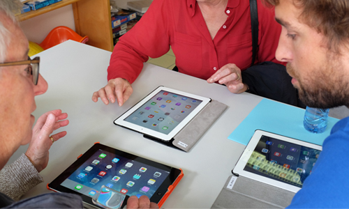 Een lesgever van de Brailleliga leert een slechtziende persoon de basisfuncties van een iPad.