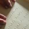 Une personne aveugle lit un livre en braille.