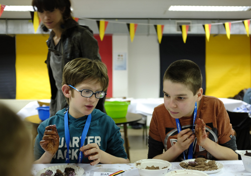 Deux enfants déficients visuels manipulent du chocolat et le roulent dans leurs mains pour en faire des truffes. 