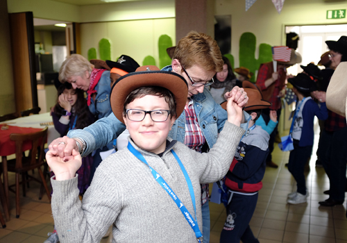 Un enfant souriant danse la country avec une accompagnatrice.