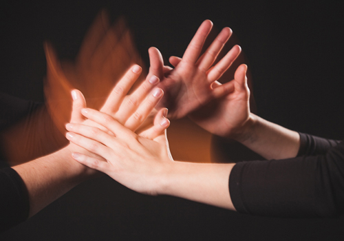 Une personne touche les mains d’une autre en train de parler la langue des signes.