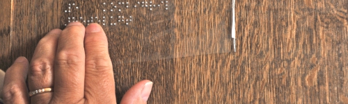 Une personne touche une armoire sur laquelle un descriptif en braille a été collé.