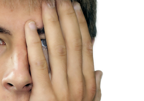 A young person using his hand to hide his left eye.