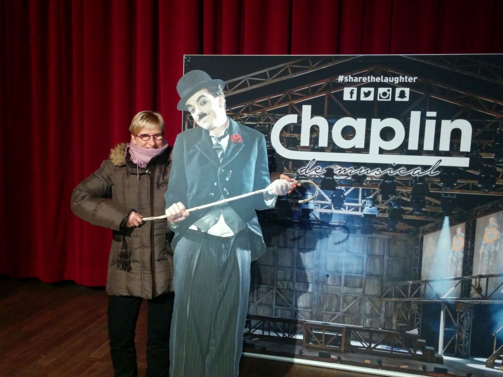 Een slechtziend lid poseert voor een reclamebord van Chaplin, the Musical