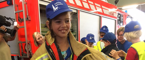 Une fille malvoyante porte l'uniforme d'un pompier. 