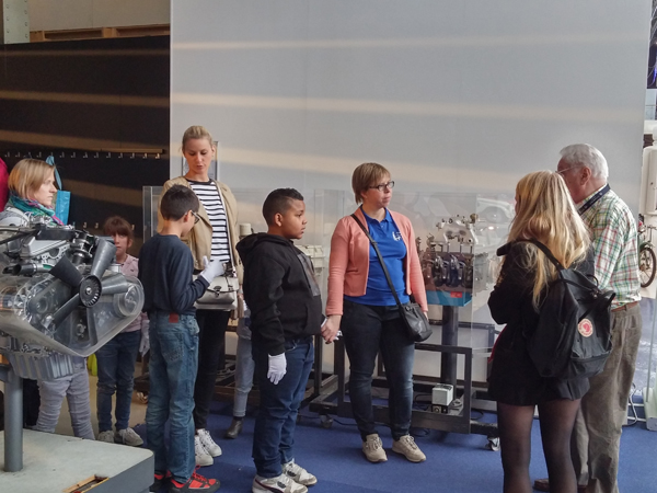 Een groep kinderen zijn in een museum en luisteren naar een gids. 