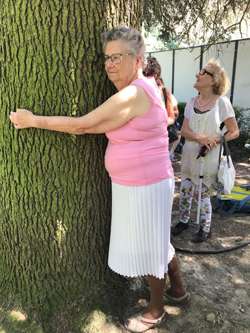 Une participante enlace le tronc de l’arbre et presse sa joue contre l’écorce.