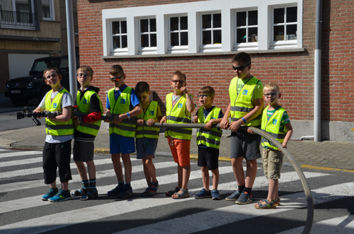 Acht kinderen houden een brandweerslang vast.