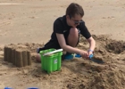 Un garçon construit un château de sable sur la plage.