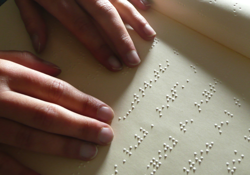 Une personne aveugle lit un livre en braille.