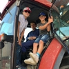 Twee kinderen en een boer in een tractor. 