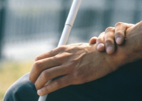 Mains d'une personne aveugle, tenant une canne blanche.