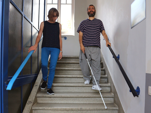 Un collaborateur de la Ligue Braille apprend à une personne avec une déficience visuelle à descendre un escalier avec l’aide de la canne blanche. 