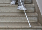 Une déficience visuelle descend un escalier avec l’aide de la canne blanche.