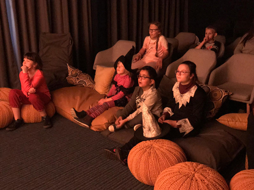 Les enfants assis sur des fauteuils dans la salle BrailleMedia en train de regarder un film.