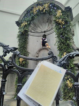 Manneken Pis habillé en Louis Braille, avec des lunettes noires, une canne blanche de locomotion et un chien-guide en peluche.