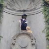 Manneken Pis habillé en Louis Braille, avec des lunettes noires, une canne blanche de locomotion et un chien-guide en peluche.