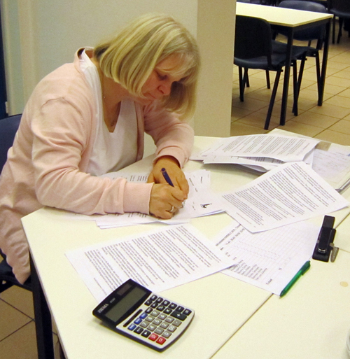 Een vrouw zit aan een tafel en vult papieren in.