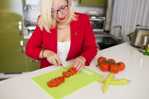Een vrouw is groenten aan het snijden. 