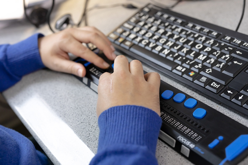 Een persoon met een visuele handicap gebruikt een aangepast toetsenbord.
