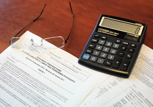 Une déclaration d'impôt sur laquelle sont déposés une paire de lunettes et une calculatrice