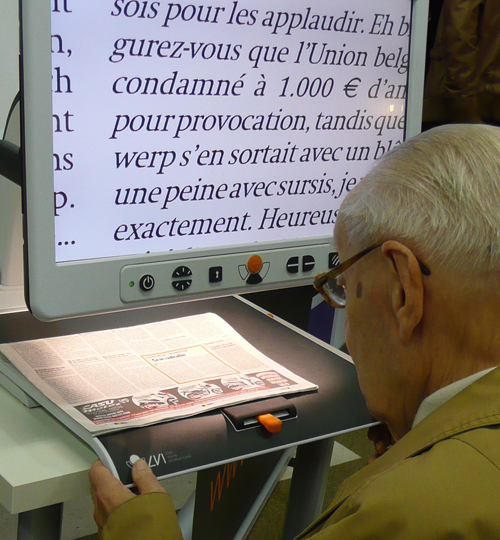 An elderly person trying out a video magnification system during the BrailleTech Exhibition.