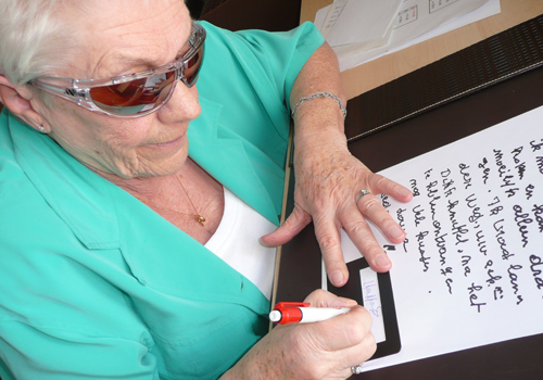 Eine sehbehinderte Person schreibt mithilfe einer Schreibhilfe.