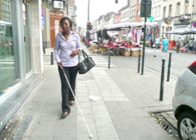 Een persoon met een visuele beperking wandelt op straat met behulp van een witte stok